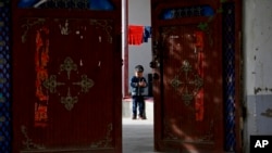 资料照片:一名维吾尔男孩在新疆和田一处团结新村的住宅院内独自一人嬉戏。(2018年9月20日)