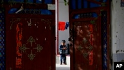 资料图:新疆和田的一名维吾尔小孩独自在家中院子里玩耍 (美联社 2018年9月20日)