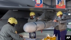 资料照片:台湾嘉义一个空军基地的地勤人员在一架F-16战机的机翼上安装导弹。(2023年1月6日)