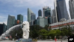资料照片: 2020年6月30日,人们在新加坡滨海湾地区拍摄鱼尾狮雕像。