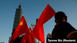 资料照:一些支持中国的台湾人在台北101大楼前举着中国国旗。(该照片拍摄时间为2016年8月22日,路透社提供)