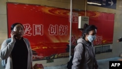 人们走过北京地铁站入口处的“爱国,创新”宣传广告牌(2018年10月19日)。