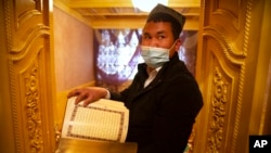 资料照：在政府组织的外国记者访问中国新疆一名维吾尔族男子阿克苏的家中时，他拿着一本阿拉伯语和维吾尔语的《古兰经》。(2021年4月20日)