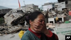 2013年4月20日(星期六),中国四川省雅安市芦山县发生里氏7级强烈地震。一名妇女在看她家遭受地震损坏后的悲痛情况。