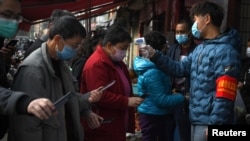 云南昆明民众戴着口罩拿着手机进行个人健康扫码方能进入超市购物。(2020年2月24日)