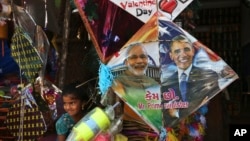 在印度海得拉巴的风筝节前夕,一名印度女孩站在一家店铺出售的画有印度总理莫迪和美国总统奥巴马头像的风筝边。(2015年1月12日)