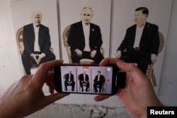 2025年2月8日,克里米亚一家美术馆的参观者在一个名为“雅尔塔2.0”的展览上用手机拍摄一幅美国总统特朗普、俄罗斯总统普京和中国领导人习近平的三人画像。