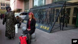 2014年5月1日,一名维吾尔族妇女在一个由中国武警重兵把守的大楼入口处休息。