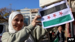 在叙利亚海滨城市拉塔基亚,一位女子亮出叙利亚反对派的旗帜。(2024年12月10日)