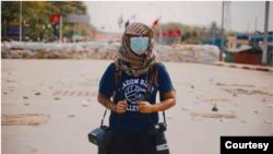 ၂၀၂၁ မတ်လတုန်းက ရန်ကုန်ဆန္ဒပြပွဲတွေအတွင်း သတင်းဓါတ်ပုံယူနေသော အမျိုးသမီးဓါတ်ပုံ သတင်းထောက်  ငြိမ်းလေး (ဓါတ်ပုံ credit: Thant Lwan Wai Chit)