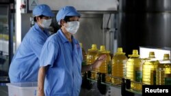 资料照片：中国山东一粮油进出口公司工厂上的工人正在用美国大豆生产瓶装豆油。（2018年7月4日）
