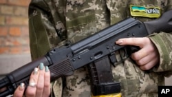 资料照片:一名武装民防妇女手持卡拉什尼科夫突击步枪在乌克兰基辅因宵禁而空荡荡的街道上巡逻。(2022年2月27日)