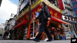 资料照片: 2024年9月4日,通勤者走过一家深受日本华人喜爱的中国杂货店。