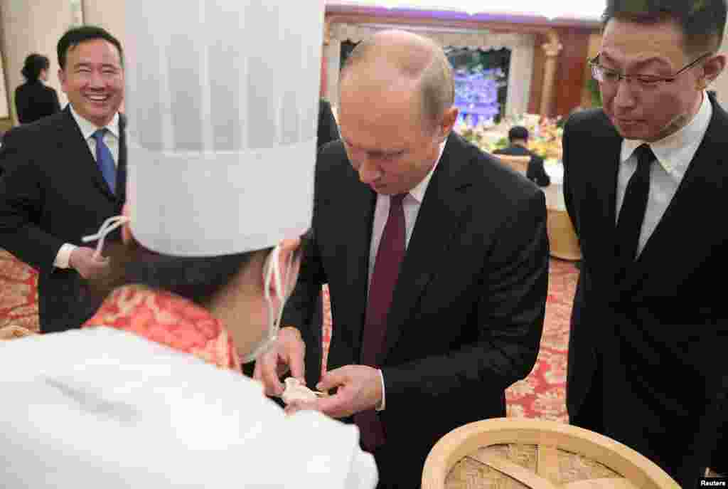 俄罗斯总统弗拉基米尔·普京2018年6月8日在中国天津参加招待会,学习做包子。