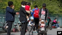 北京市民带着孩子在一处商业大楼广场上游玩 (美联社 2021年5月10日)