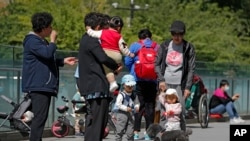 北京市民带着孩子在一处商业大楼广场上游玩。(2021年5月10日)