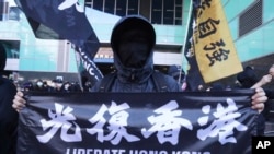 资料照- 一位人在台湾的香港居民手举“Liberate Hong Kong”横幅在台湾街头抗议中国当局扣留12名香港人。(美联社照片)