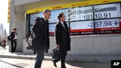 人们从日本东京一证交所外的电子股指显示器旁走过。(资料图)