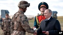 俄罗斯总统普京(右)在中俄边界附近举行的“东方-2018”战略军演后给一名中国军人颁发勋章。(2018年9月13日)