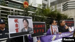 资料照:香港抗议者在北京驻香港机构中联办前手举铜锣湾书店失踪老板桂民海的照片。 (2016年1月19日)