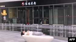 一名男子在北京一家商场的喷泉旁睡觉。(2024年7月18日)