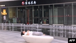 资料照:一名男子在北京一家商场的喷泉旁睡觉。(2024年7月18日)