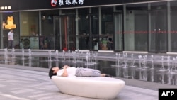 一名男子在北京一家商场的喷泉旁睡觉。(2024年7月18日)