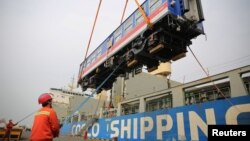 中国山东省青岛港的工人将一辆出口斯里兰卡的高铁车厢装入集装箱里。(2020年3月3日)