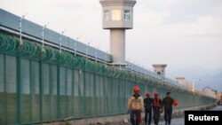 中国新疆维吾尔自治区达坂城的官方所谓的职业技能教育中心的围栏旁边,有工人走过。(2018年9月4日)