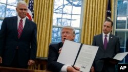美国副总统彭斯(左)和白宫办公厅主任普里巴斯(右)目视总统川普展示宣布美国退出TPP的行政令。(2017年1月23日)