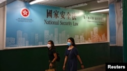 行人走过香港政府在街头张贴的港版国安法宣传标语。(2020年6月29日)