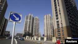 资料照 - 一位妇女骑着三轮车,车上载一名儿童。周围是北京通州区居民楼群。