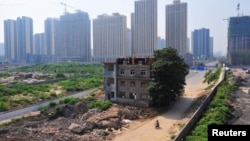 资料照:中国陕西西安市一个建筑工地的中央矗立着被拆了一半的楼房,里面居住着因拆迁纠纷拒绝搬走的一家七口人。(2013年8月14日)