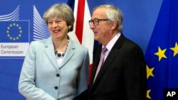 英国首相特蕾莎.梅(左)和欧洲委员会主席容克在布鲁塞尔谈判前握手