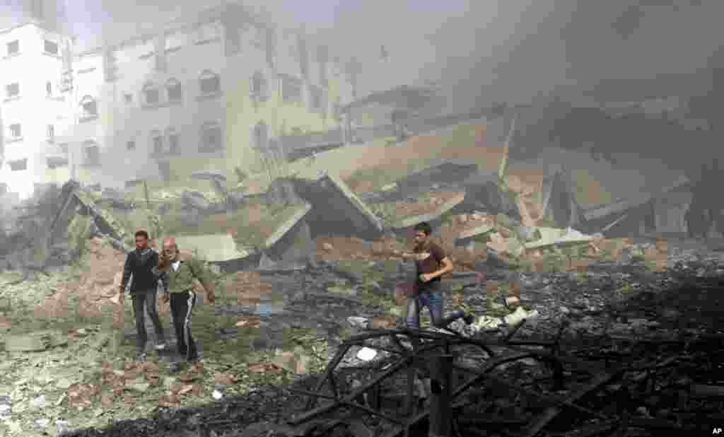 2012年11月18日,在以色列对加沙市发动一次空袭后,巴勒斯坦人匆匆逃离一座受损建筑。