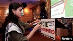 Nhà hoạt động Natalia Latif dán tấm biển kêu gọi bỏ phiếu không cho ai cả trong buổi tụ tập vào đêm bầu cử khi các cử tri theo Đảng Dân chủ và Đảng Cộng hòa tổ chức cuộc bầu cử tổng thống sơ bộ ở bang Michigan, tại Dearborn, Michigan, Mỹ, ngày 27 tháng 2 năm 2024.
