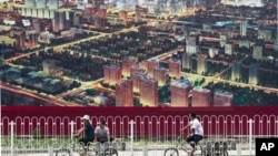 人们骑自行车经过北京一座广告牌,广告牌显示了北京中央商务区的景象(资料照片)