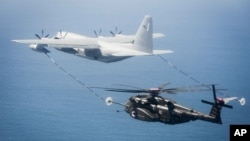 美军一架MH-53E海龙式直升机与一架KC-130加油机在维吉尼亚州诺福克海军基地附近上空进行演练。(2016年3月资料照)