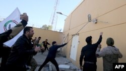 伊拉克示威者冲击美国驻巴格达大使馆的外墙,抗议者谴责美国对伊拉克境内伊朗支持的民兵发动空袭。 2019年12月31日,法新社照片)