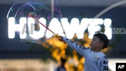 一名儿童在北京华为标识附近玩泡泡(2019年5月20日)。
