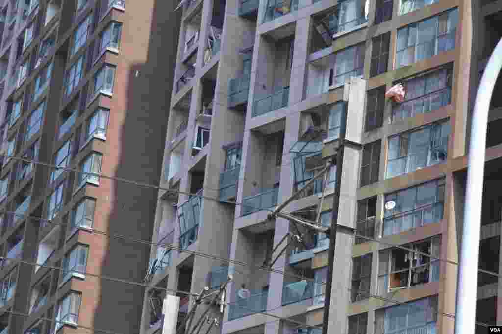 天津爆炸事故现场,核心爆炸区周围多座居民楼窗户被震碎,高速公路桥梁受损,多辆大货车被炸翻,小汽车起火或被砸,多名当地居民仍逗留在事故现场。(美国之音记者东方拍摄)