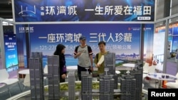 中国广东省深圳市一个房地产博览会的推销员在向客户介绍楼型。(2024年10月12日)