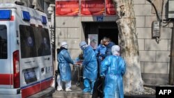 身穿防护服的医务人员把一名新冠病毒疑似感染的病人从武汉市一座居民楼里抬出。(2020年1月30日)