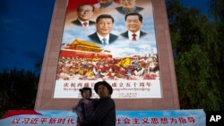 资料照:在西藏拉萨布达拉宫外,一名男子抱着一个小女孩在一幅宣传中国历届领导人的画像前拍照。(2021年6月1日)