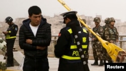 一名中国警察在新疆喀什检查一名男子的身份证件。(2017年3月24日)