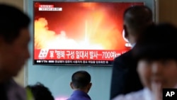 韩国旅客在首尔火车站观看朝鲜发射弹道导弹的有关资料图像。(2017年5月14日)