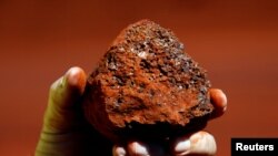 资料照:一名澳大利亚矿工手握澳西部地区产出的一块铁矿石。