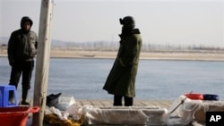 中国渔民在丹东的河边卖鱼,河对岸是朝鲜边境城镇新义州