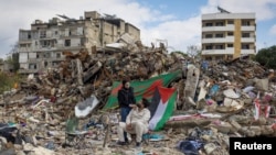 以色列和真主党停火第二天,一对青年坐在黎巴嫩南部城镇纳巴蒂耶的一栋建筑的废墟旁,他们的家人在这栋建筑里开了一家商店。(2024年11月28日)