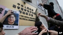 香港抗议者在北京驻香港机构中联办前贴上铜锣湾书店失踪老板桂民海的照片。 (2016年1月3日)